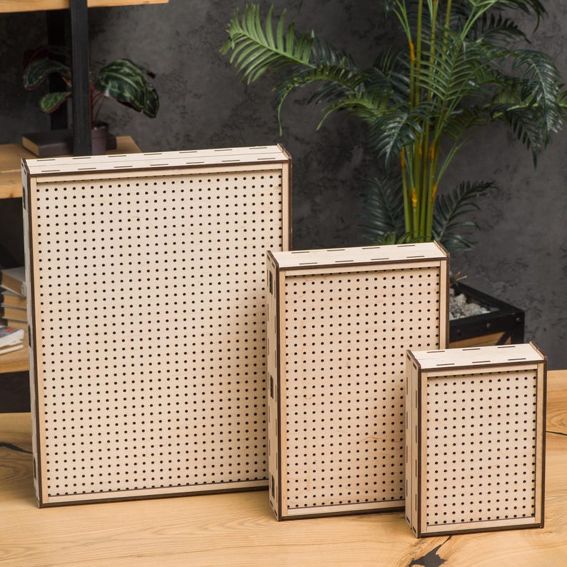 May include: Three wooden boxes with a grid pattern on the front. The boxes are different sizes and are arranged in a row from largest to smallest.