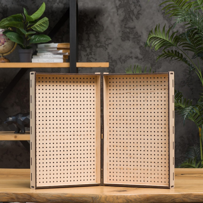 May include: A wooden box with two hinged panels, each with a grid of small holes. The box is open and the panels are facing outward.
