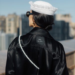 May include: A black satin jacket with a pearl strap and a white label on the back that says "SO... by N...