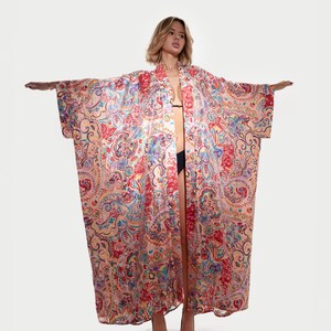 May include: A long, open-front kimono robe with a vibrant paisley pattern in shades of red, blue, and yellow. The robe is made of a lightweight fabric and has wide sleeves. The model is wearing black heels.