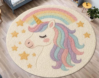 May include: A round, cream-colored area rug featuring a central unicorn head with a gold horn, closed eyes, and a flowing mane in pastel shades of pink, purple, and blue. A rainbow arches above the unicorn, surrounded by scattered yellow stars.