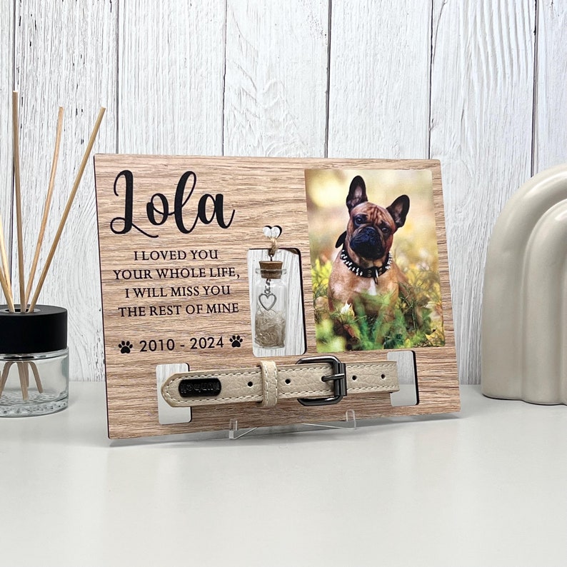 May include: A wooden pet memorial frame with a photo of a dog, a small glass bottle, and a beige dog collar. The frame includes the name "Lola" and the text "I loved you your whole life, I will miss you the rest of mine 2010-2024."