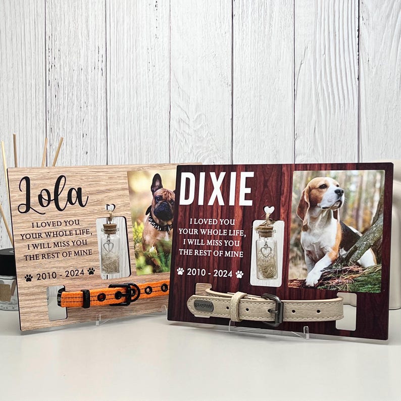 May include: Two wooden pet memorial frames with photos of dogs, names, and dates. Each frame has a small glass bottle with a heart charm and a dog collar. One collar is orange, the other is beige.