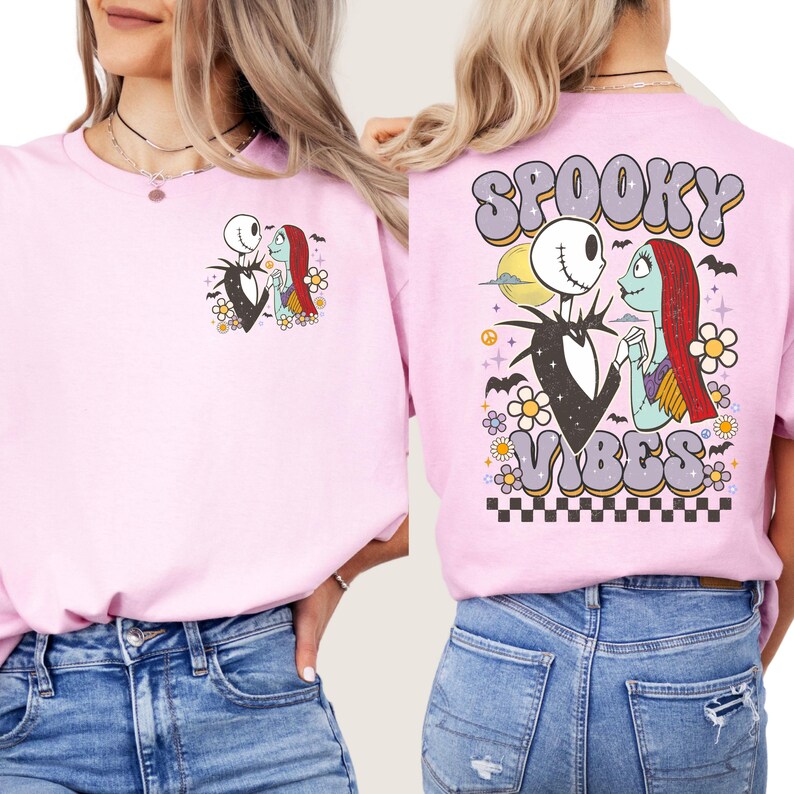 Puede incluir: Sudadera rosa claro con un dise&ntilde;o de Jack Skellington y Sally de Pesadilla antes de Navidad. La parte trasera de la sudadera tiene las palabras "Spooky Vibes" en una fuente retro, con murci&eacute;lagos, flores y un patr&oacute;n de tablero de ajedrez.