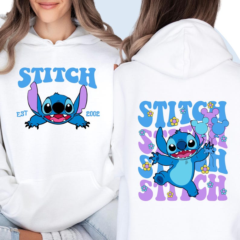 May include: White hoodie with a blue Stitch character graphic. The front of the hoodie says "Stitch Est 2002". The back of the hoodie has a repeated "Stitch" graphic with blue Stitch character and purple flowers.