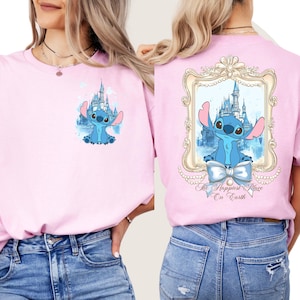 Puede incluir: Camiseta rosa con un personaje azul Stitch y un gr&aacute;fico de castillo en la parte delantera. La parte posterior de la camiseta tiene una imagen enmarcada de Stitch con un castillo y el texto "The Happiest Place On Earth".