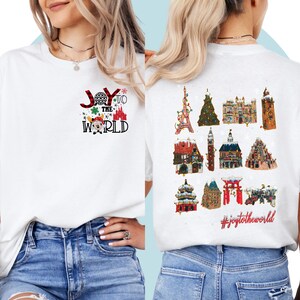 May include: White t-shirt with a red and black plaid design that says "Joy to the World" with a Mickey Mouse head and a Christmas tree. The back of the shirt has a graphic of different Disney park icons with the hashtag #joytotheworld.