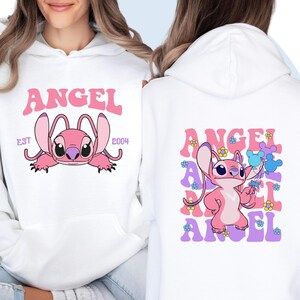 May include: White hoodie with a pink Stitch character and the text "ANGEL EST 2004" on the front. The back of the hoodie features a pink Stitch character with the text "ANGEL" repeated in a colorful, retro font.