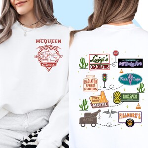 May include: White sweatshirt with a red graphic of Lightning McQueen from the Cars movie. The back of the sweatshirt has a white graphic of a road trip route with various landmarks from the movie, including Luigi's Casa Della Tires, Radiator Springs Curios, Cozy Cone Motel, and Fillmore's.