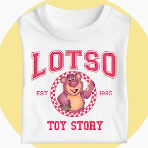 May include: White t-shirt with a graphic of Lotso, the bear from Toy Story, inside a red and white checkered circle. The word "LOTSO" is printed above the bear in red block letters, with "EST 1995" and "TOY STORY" below.