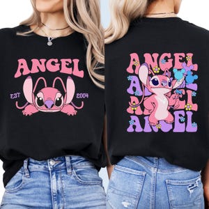 May include: Black t-shirt with a pink and purple graphic of Stitch from Lilo & Stitch. The graphic says "Angel" in a retro font with flowers and the text "Est 2004".