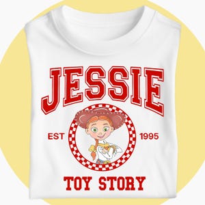 May include: White t-shirt with the name "JESSIE" in red varsity lettering. Below is a cartoon image of Jessie from Toy Story, encircled by a red and white checkered pattern. The text "EST 1995" and "TOY STORY" are also in red.
