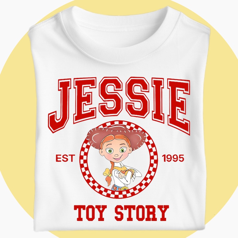 May include: White t-shirt with the name "JESSIE" in red varsity lettering. Below is a cartoon image of Jessie from Toy Story, encircled by a red and white checkered pattern. The text "EST 1995" and "TOY STORY" are also in red.