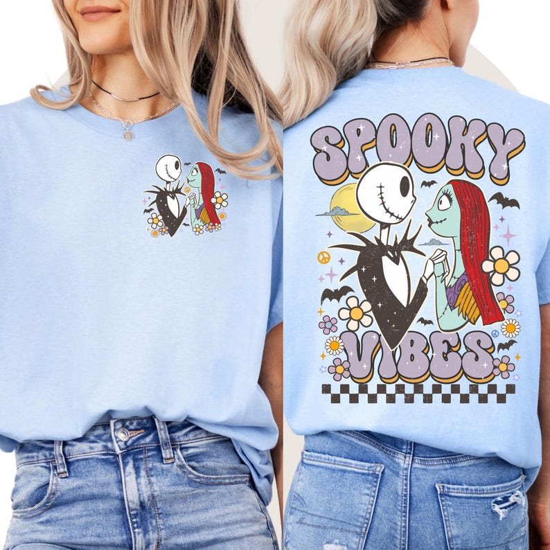 Puede incluir: Camiseta azul claro con una imagen de dibujos animados de Jack Skellington y Sally. La parte posterior de la camiseta tiene las palabras "Spooky Vibes" en una fuente retro, con una luna, murci&eacute;lagos y flores. La camiseta es de material suave.