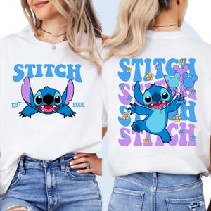 May include: Two white t-shirts with a blue Stitch character graphic. The front shirt has the text "Stitch Est 2002". The back shirt has the text "Stitch" repeated multiple times with flowers and a blue Stitch character holding balloons.