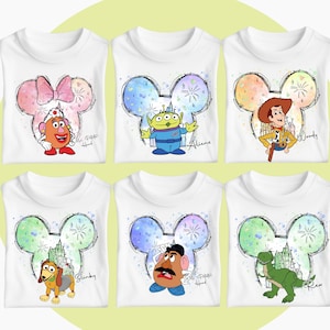 May include: Six white t-shirts with a colorful Mickey Mouse head design featuring different Disney characters. The characters include Mr. Potato Head, Alien, Woody, Slinky Dog, Mr. Potato Head, and Rex.