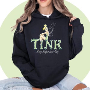 May include: Black hooded sweatshirt with a green Tinkerbell graphic and the text "TINK being Perfect Isn't Easy".