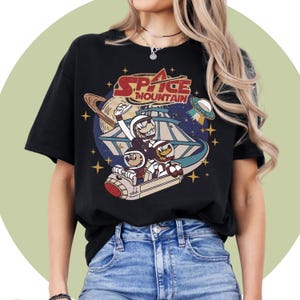 May include: Black t-shirt featuring a vintage-style graphic of Mickey Mouse and friends riding a spaceship. The graphic includes the text "Space Mountain".