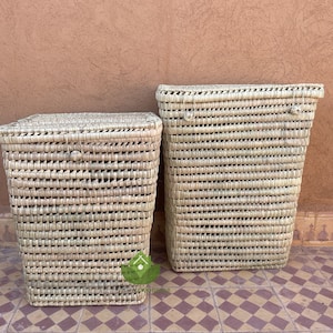 Puede incluir: Dos cestas de almacenamiento tejidas con materiales naturales. Las cestas son rectangulares y de color marrón claro. Están sobre un suelo de baldosas.