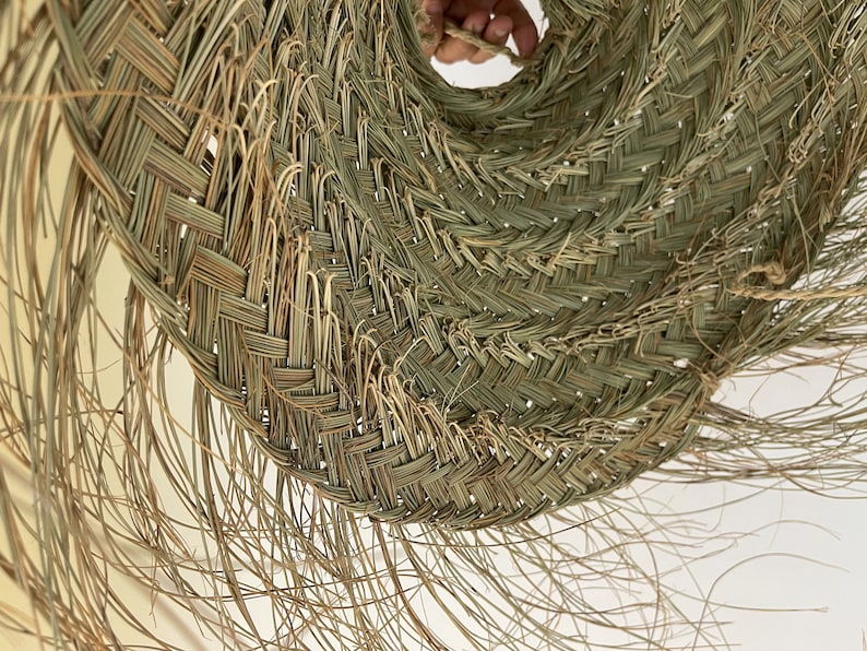 Puede incluir: Primer plano de un sombrero de paja tejido de color marr&oacute;n claro natural. El sombrero est&aacute; hecho de hebras de paja tejidas apretadamente, creando una superficie texturizada. El sombrero tiene un ala ancha y una corona ligeramente puntiaguda.