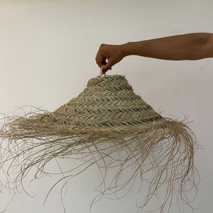 Puede incluir: Una pantalla de l&aacute;mpara grande, redonda y tejida hecha de materiales naturales con una franja de hebras largas y delgadas. La pantalla de la l&aacute;mpara es de color marr&oacute;n claro y tiene un patr&oacute;n tejido.