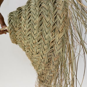 Puede incluir: Un gran sombrero de paja tejido con un ala ancha y una larga franja que fluye. El sombrero est&aacute; hecho de materiales naturales y tiene un aspecto r&uacute;stico y hecho a mano.