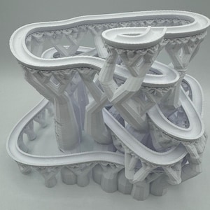 Può includere: Modello 3D stampato in bianco di una struttura complessa a più livelli con una serie di percorsi tortuosi interconnessi. La struttura assomiglia a un labirinto o a una città in miniatura.