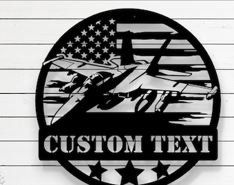 Puede incluir: Diseño de archivo de corte por láser en blanco y negro de un avión de combate volando sobre una bandera estadounidense con estrellas y rayas. El diseño incluye el texto "CUSTOM TEXT" debajo del avión. El archivo está disponible en los formatos CDR, AI, SVG, DXF y PDF.
