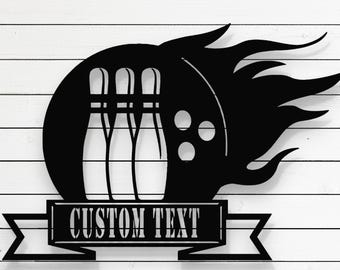 May include: Black laser-cut metal bowling-themed wall art. The design features bowling pins, a bowling ball, and flames. The text "LASER CUT FILES" is at the top, and "CUSTOM TEXT" is in a banner below. Includes file formats: CDR, AI, SVG, DXF, and PDF.
