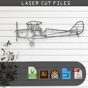 Op de afbeelding: Zwarte metalen lasergesneden vliegtuig wandkunst. Het tweedekkerontwerp heeft een propeller, vleugels en staart, gemonteerd op een witte houten plank achtergrond. De tekst "LASER CUT FILES" staat bovenaan. Inclusief CDR-, AI-, SVG-, DXF- en PDF-bestandsformaten.