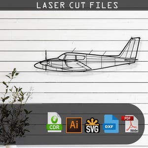 以下が含まれることがあります： 単発エンジンの飛行機の白黒の線画イラスト。画像は「LASER CUT FILES」とラベル付けされており、CDR、AI、SVG、DXF、PDFのファイル形式が含まれています。