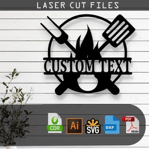 May include: Black metal laser-cut sign with a barbecue theme. The design includes a circle with a spatula, fork, and flames, and the words "CUSTOM TEXT". The sign is mounted on a white wooden background. The words "LASER CUT FILES" are at the top.
