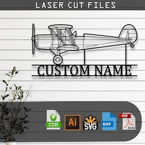 May include: A black metal wall art piece featuring a biplane silhouette above the text CUSTOM NAME. The design includes laser cut file icons for CDR, AI, SVG, DXF, and PDF formats. The text LASER CUT FILES appears at the top of the display.