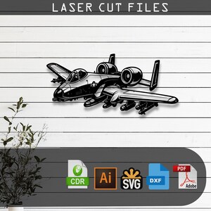 May include: A black and white digital illustration of an A-10 Thunderbolt II aircraft featuring a cockpit, dual engines, and wing-mounted armaments. The text LASER CUT FILES appears at the top, with file format icons for CDR, Ai, SVG, DXF, and PDF below.