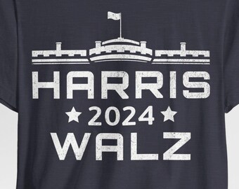 May include: A navy blue t-shirt with a white distressed graphic of a building with a flag on top. The text "HARRIS 2024 WALZ" is below the building.