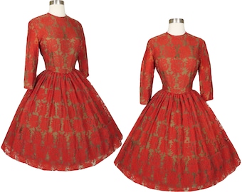 May include: A red lace dress with a fitted bodice and a full skirt. The dress has a round neckline and three-quarter sleeves. The lace pattern is a floral design with a gold thread.