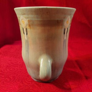 May include: A light blue ceramic vase with a white floral design and two handles. The vase has a glazed finish and a slightly iridescent sheen.