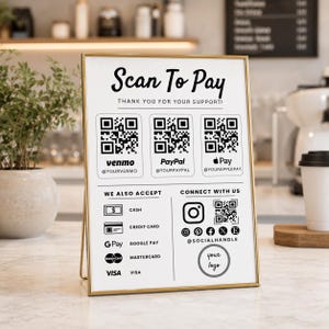 Könnte beinhalten: Ein rechteckiges Schild mit goldenem Rahmen und weißem Hintergrund, das den Text Scan To Pay, Thank You For Your Support sowie drei QR-Codes für Venmo, PayPal und Apple Pay zeigt. Es listet Zahlungsmethoden und Social-Media-Symbole auf.