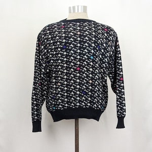 May include: Black sweater with a white and multi-colored geometric pattern.