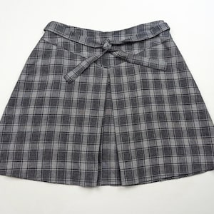 May include: A gray and white plaid skirt with a tie at the waist.