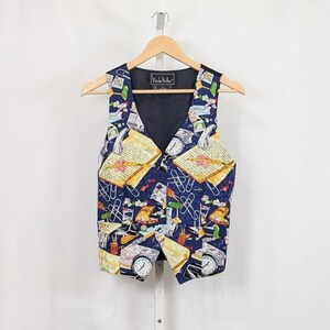 May include: A navy blue vest featuring a repeating pattern of office supplies including yellow notebooks, silver paperclips, pens, and clocks. The garment has a V-neckline, a button-front closure, and a black interior lining with a Nicole Miller label.