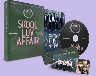May include: A BTS Skool Luv Affair 2nd mini album set including a dark green rectangular case with pink text, a black circular disc, a rectangular green card, and a small rectangular photo card featuring seven individuals in white shirts.