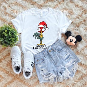 May include: White t-shirt with a cartoon rooster in a Santa hat, and the words "MERRY CHRISTMAS". Accompanied by light blue denim shorts, white trainers, and a Mickey Mouse soft toy. A festive holiday theme.