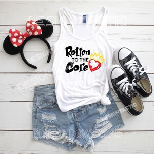 May include: A white tank top with the text "Rotten to the Core" and a heart graphic, paired with denim shorts, black sneakers, and a Minnie Mouse ear headband with a red polka dot bow. A casual outfit.