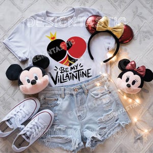 Pu&ograve; includere: Maglietta bianca con un design a forma di cuore rosso e nero e il testo "Be My Villaintine". Sono anche raffigurati un paio di orecchie di Topolino rosse e dorate, un peluche di Topolino e un peluche di Minnie Mouse.