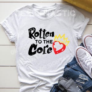 May include: White t-shirt with the text "Rotten to the Core" in black, a red heart, and a yellow crown graphic. The shirt is paired with blue jeans and white sneakers.