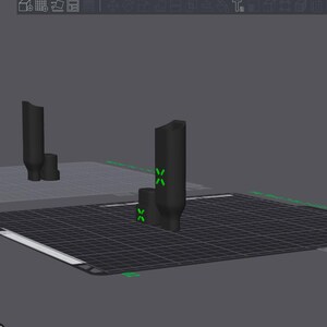 May include: A 3D render of a black, cylindrical object with a smaller base, set on a gridded surface. Green cross markers are visible. The background is a plain grey colour.