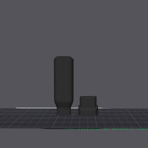 May include: Two black objects, one cylindrical and one square, on a dark grey grid. The cylindrical object has a rectangular base. The background is a solid grey. The objects appear to be 3D models.