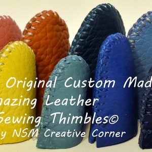 May include: A collection of 10 leather sewing thimbles in various colors, including red, pink, orange, yellow, blue, and purple. The thimbles are all handmade and have a white stitching detail around the top edge. The text "The Original Custom Made Amazing Leather Sewing Thimbles&reg; by NSM Creative Corner" is displayed below the thimbles.
