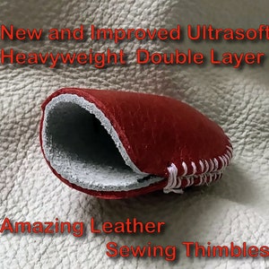 Puede incluir: Un dedal de costura de cuero rojo con una costura blanca. El dedal es de doble capa y tiene una sensaci&oacute;n suave y ultra suave. "New and Improved Ultrasoft Heavyweight Double Layer Amazing Leather Sewing Thimbles" est&aacute; escrito en rojo sobre un fondo blanco.